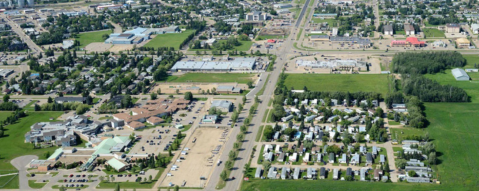 Aerial view of a suburban area with residential homes, commercial buildings, and green fields.